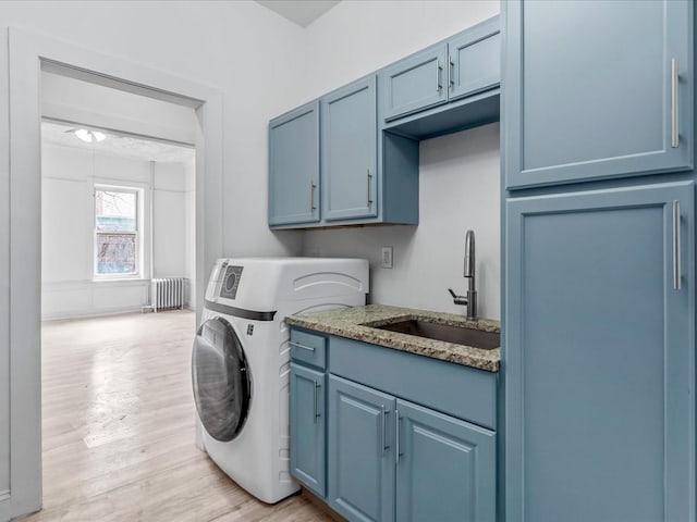 washroom featuring a sink, light wood-type flooring, cabinet space, washer / clothes dryer, and radiator heating unit