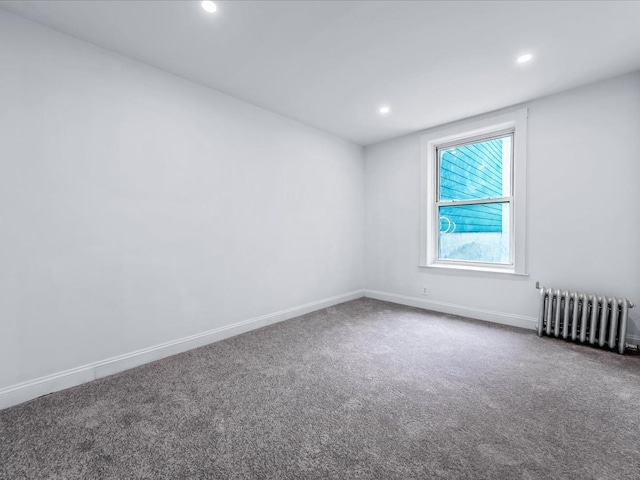 empty room featuring carpet floors, radiator heating unit, baseboards, and recessed lighting