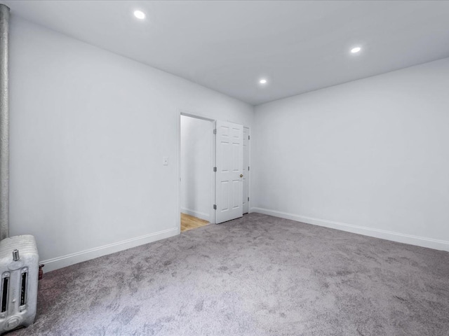 spare room with radiator heating unit, baseboards, carpet flooring, and recessed lighting