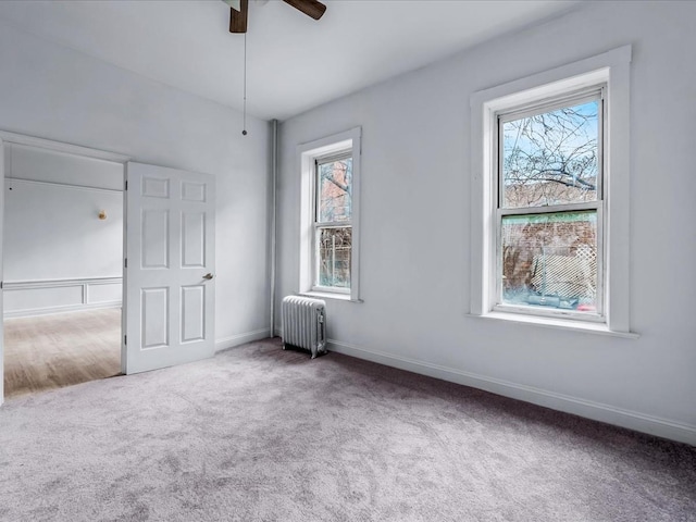 unfurnished bedroom with radiator, carpet, multiple windows, and baseboards