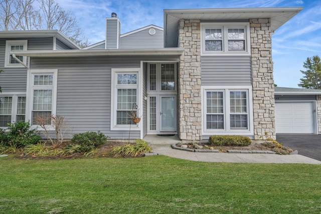 view of front of property featuring a front yard, an attached garage, driveway, and a chimney