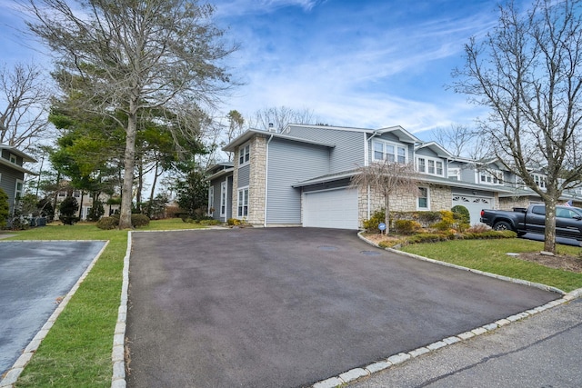 view of home's exterior with stone siding, driveway, and an attached garage