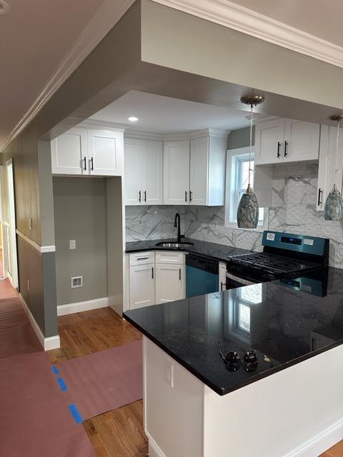 kitchen featuring dark countertops, ornamental molding, stainless steel gas stove, a sink, and dishwashing machine