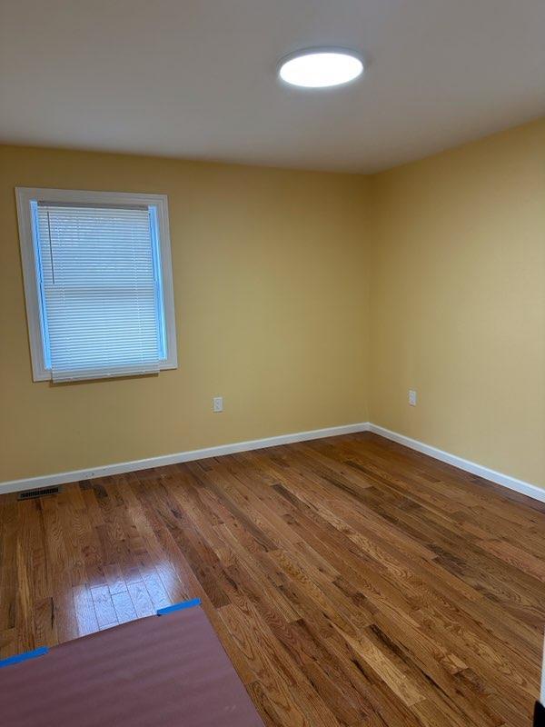 unfurnished room with dark wood-type flooring, visible vents, and baseboards