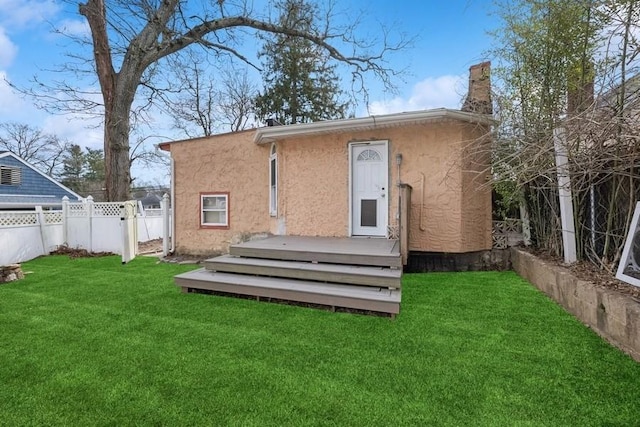 back of house featuring a wooden deck, a yard, stucco siding, and fence