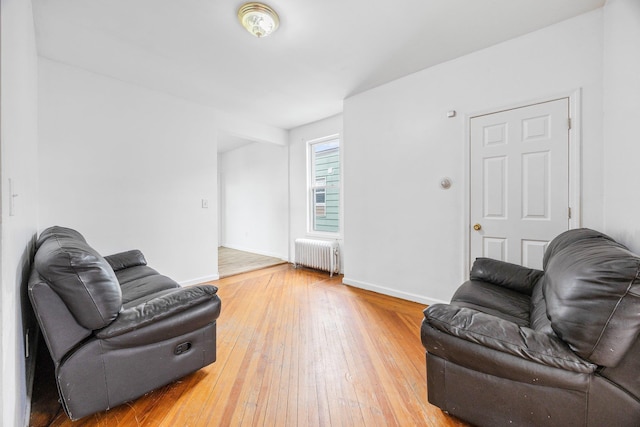 living room featuring light wood-type flooring, baseboards, and radiator heating unit
