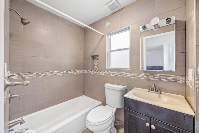 bathroom featuring shower / bath combination, visible vents, toilet, vanity, and tile walls