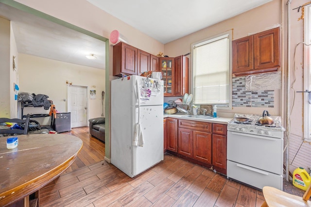 kitchen featuring light wood-style floors, white appliances, glass insert cabinets, and a sink