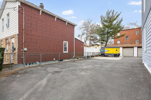 view of home's exterior with a garage, brick siding, and fence