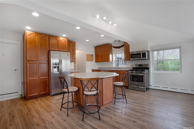 kitchen featuring a kitchen island, appliances with stainless steel finishes, baseboard heating, light countertops, and light wood-style floors