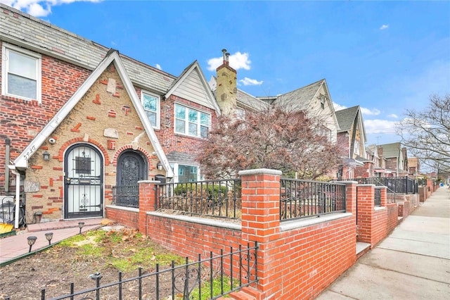 view of front facade with fence, brick siding, and a chimney