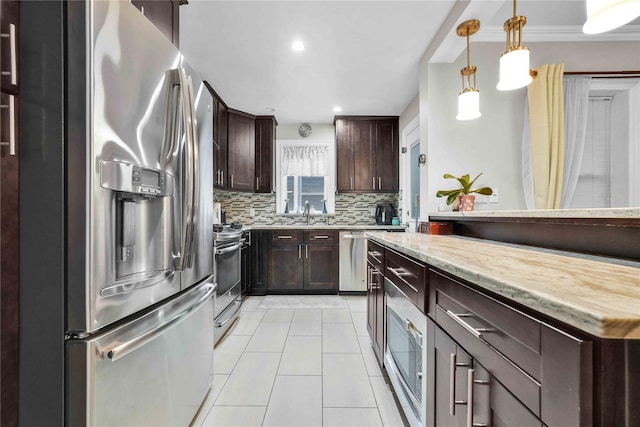 kitchen with light tile patterned floors, stainless steel appliances, hanging light fixtures, dark brown cabinets, and tasteful backsplash