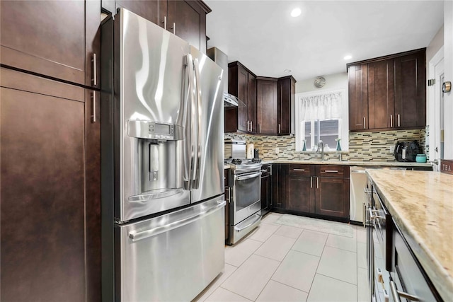 kitchen featuring a sink, stainless steel appliances, dark brown cabinetry, light tile patterned floors, and decorative backsplash