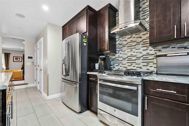 kitchen with tasteful backsplash, stainless steel appliances, wall chimney exhaust hood, light tile patterned floors, and dark brown cabinets