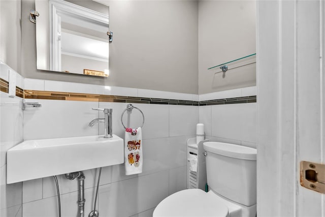 bathroom with tile walls, toilet, and a sink