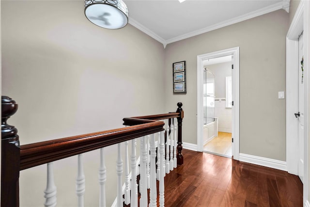 hallway with hardwood / wood-style flooring, an upstairs landing, baseboards, and ornamental molding