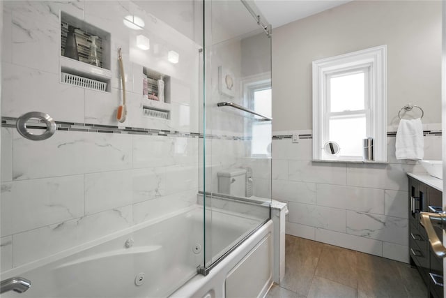 bathroom with vanity, tile walls, and a combined bath / shower with jetted tub