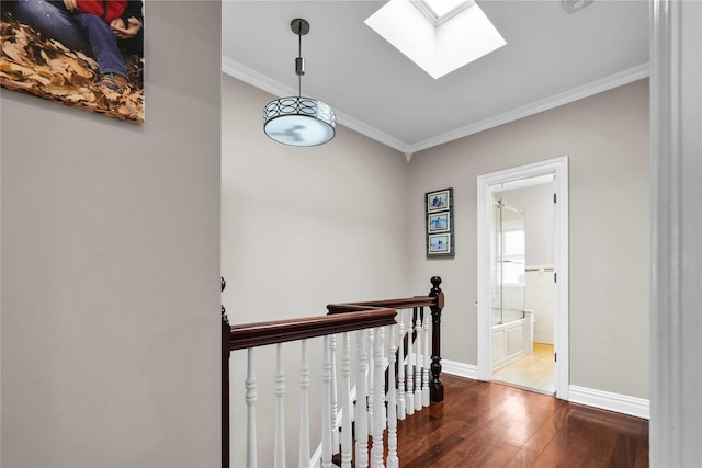 hall with baseboards, hardwood / wood-style floors, an upstairs landing, ornamental molding, and a skylight