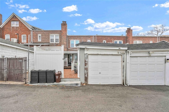 view of front facade featuring community garages, a gate, fence, and brick siding