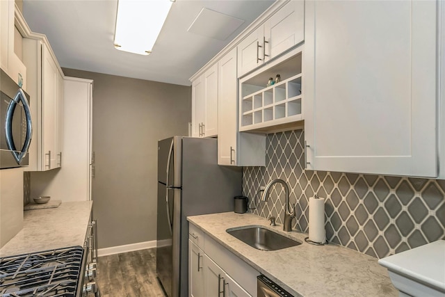 kitchen with a sink, dark wood finished floors, freestanding refrigerator, decorative backsplash, and baseboards