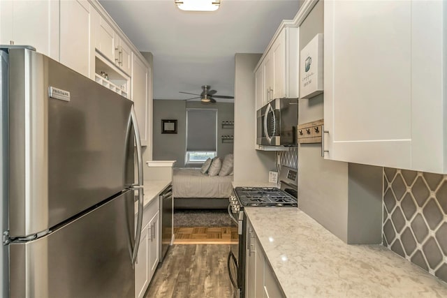 kitchen featuring light stone counters, stainless steel appliances, ceiling fan, and white cabinetry