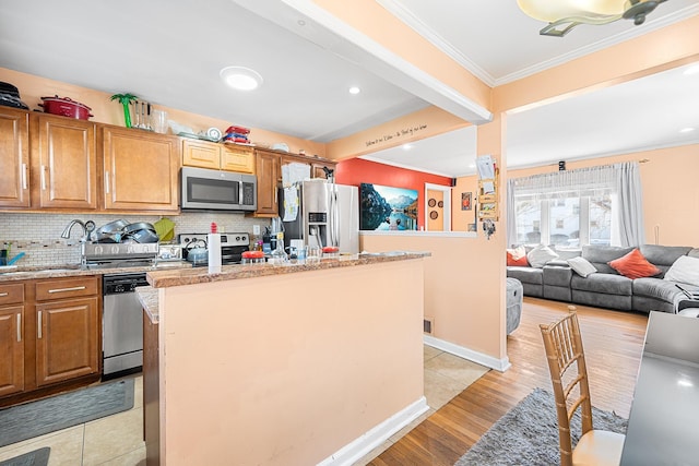 kitchen with backsplash, appliances with stainless steel finishes, ornamental molding, and a center island