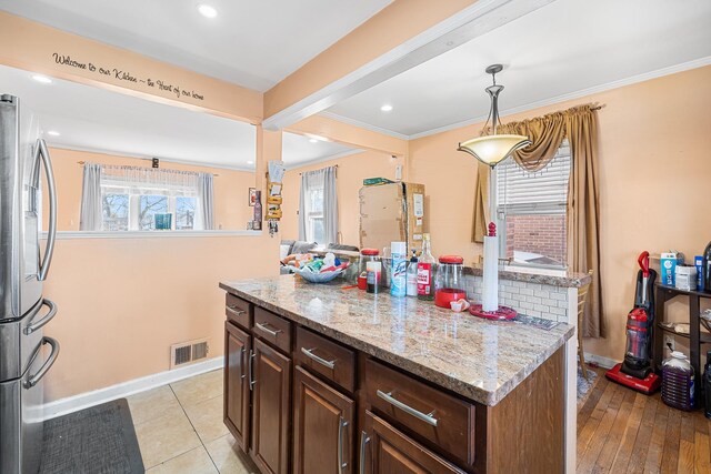 kitchen with visible vents, a center island, freestanding refrigerator, crown molding, and baseboards