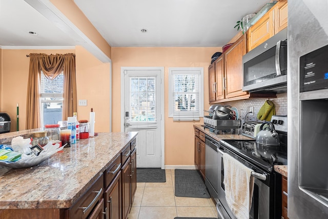 kitchen with light tile patterned floors, plenty of natural light, tasteful backsplash, and appliances with stainless steel finishes