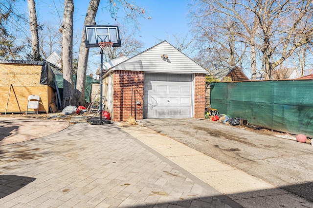 detached garage featuring driveway and fence