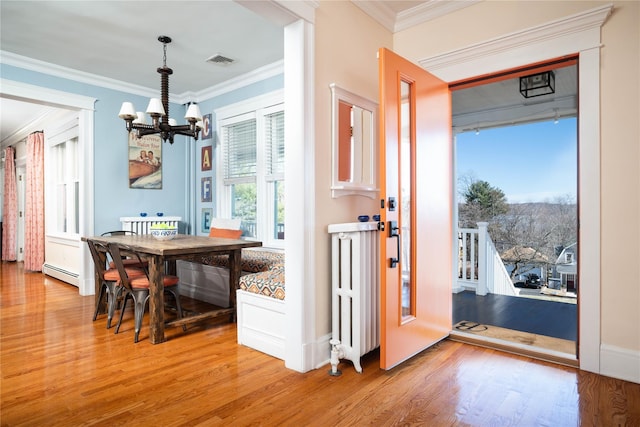 dining space with a baseboard heating unit, an inviting chandelier, light wood-style floors, and visible vents