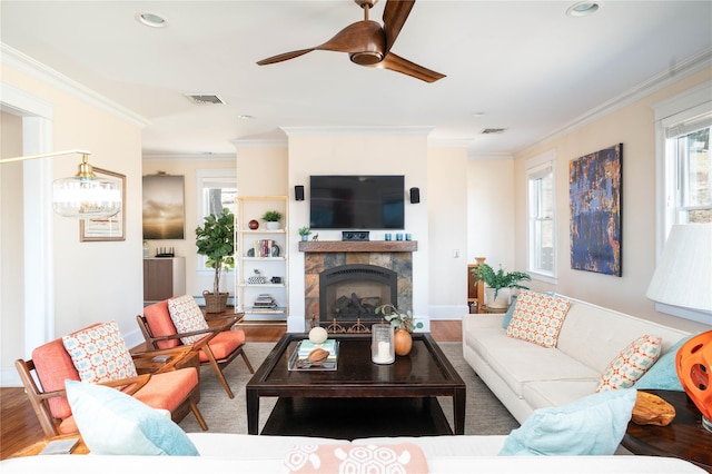 living room with visible vents, wood finished floors, a ceiling fan, and ornamental molding