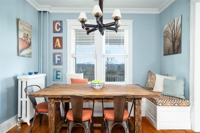 dining room with wood finished floors, an inviting chandelier, ornamental molding, and radiator heating unit