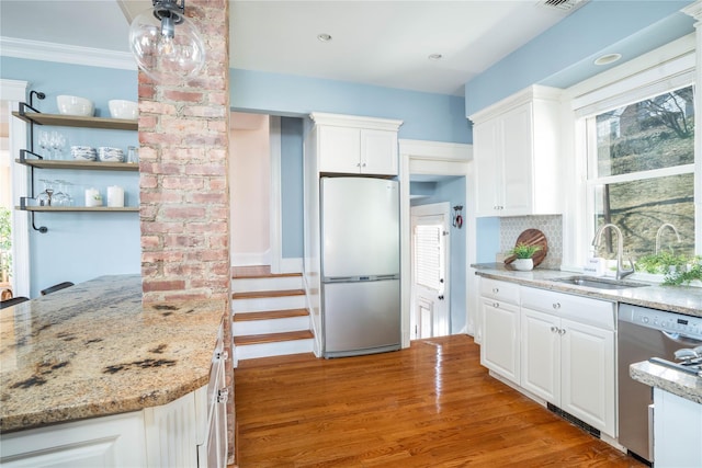 kitchen with tasteful backsplash, white cabinetry, stainless steel appliances, and a sink