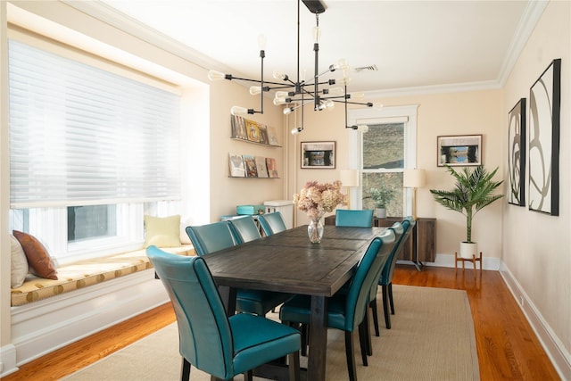 dining space featuring an inviting chandelier, wood finished floors, baseboards, and ornamental molding