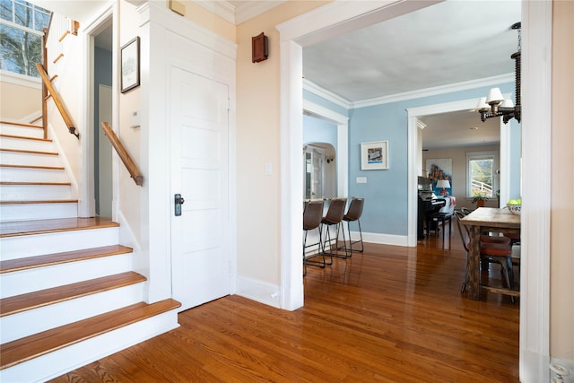 staircase featuring baseboards, arched walkways, wood finished floors, and ornamental molding