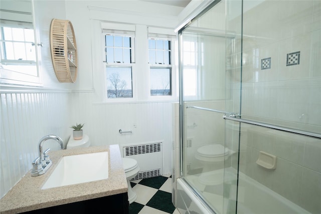 full bathroom featuring tile patterned floors, toilet, radiator heating unit, shower / bath combination with glass door, and vanity