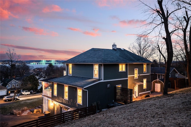 rear view of property featuring a fenced front yard, a chimney, and a shingled roof