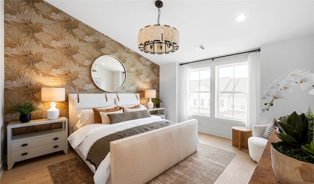 bedroom featuring a chandelier, light wood-style flooring, visible vents, and wallpapered walls