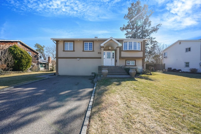 bi-level home featuring driveway, a front yard, and stucco siding