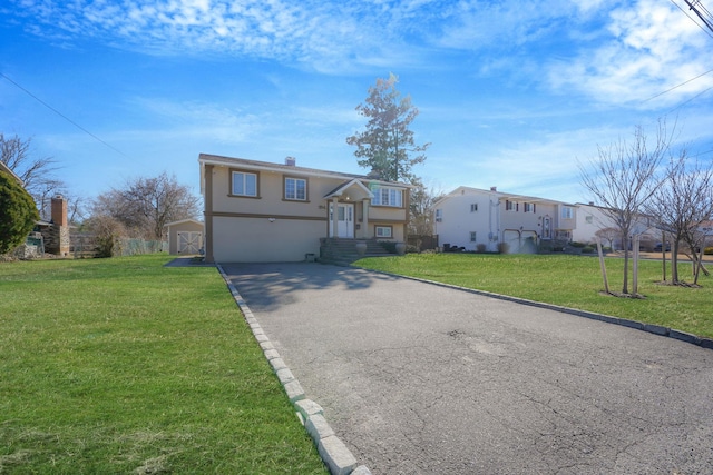 view of front of house featuring a garage, stucco siding, a front lawn, and aphalt driveway