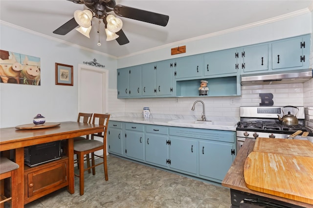 kitchen featuring crown molding, under cabinet range hood, stainless steel range with gas stovetop, blue cabinets, and a sink