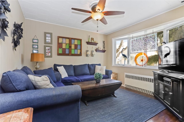 living area featuring radiator, dark wood-type flooring, a ceiling fan, and crown molding