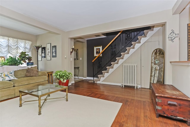 living area with stairway, baseboards, wood finished floors, and radiator heating unit