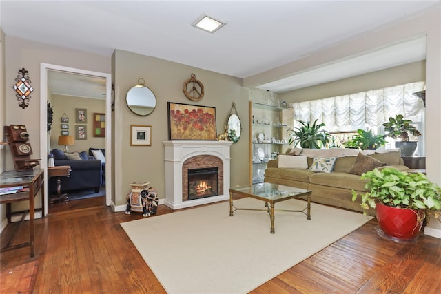 living room with dark wood-style floors, a glass covered fireplace, and baseboards