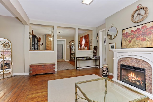 living area with a stone fireplace, baseboards, and wood finished floors