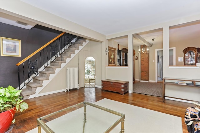 living area with stairway, radiator, visible vents, and wood finished floors