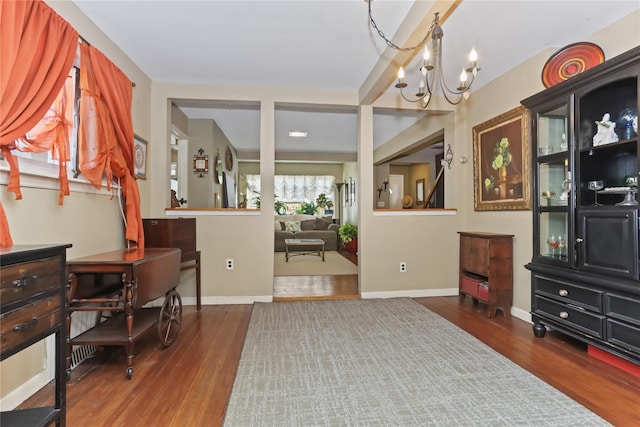 interior space with baseboards, a notable chandelier, and wood finished floors