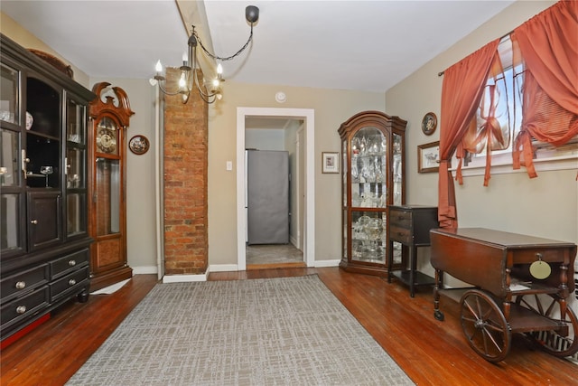 foyer entrance featuring dark wood finished floors, an inviting chandelier, and baseboards