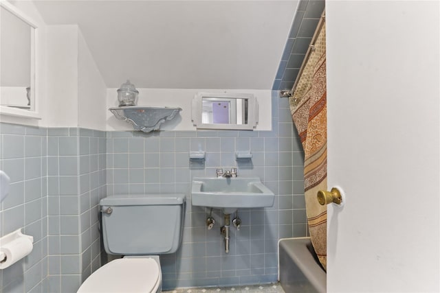 bathroom featuring curtained shower, toilet, tile walls, and a sink