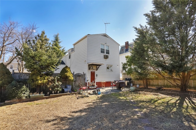 rear view of property with a fenced backyard and a patio area